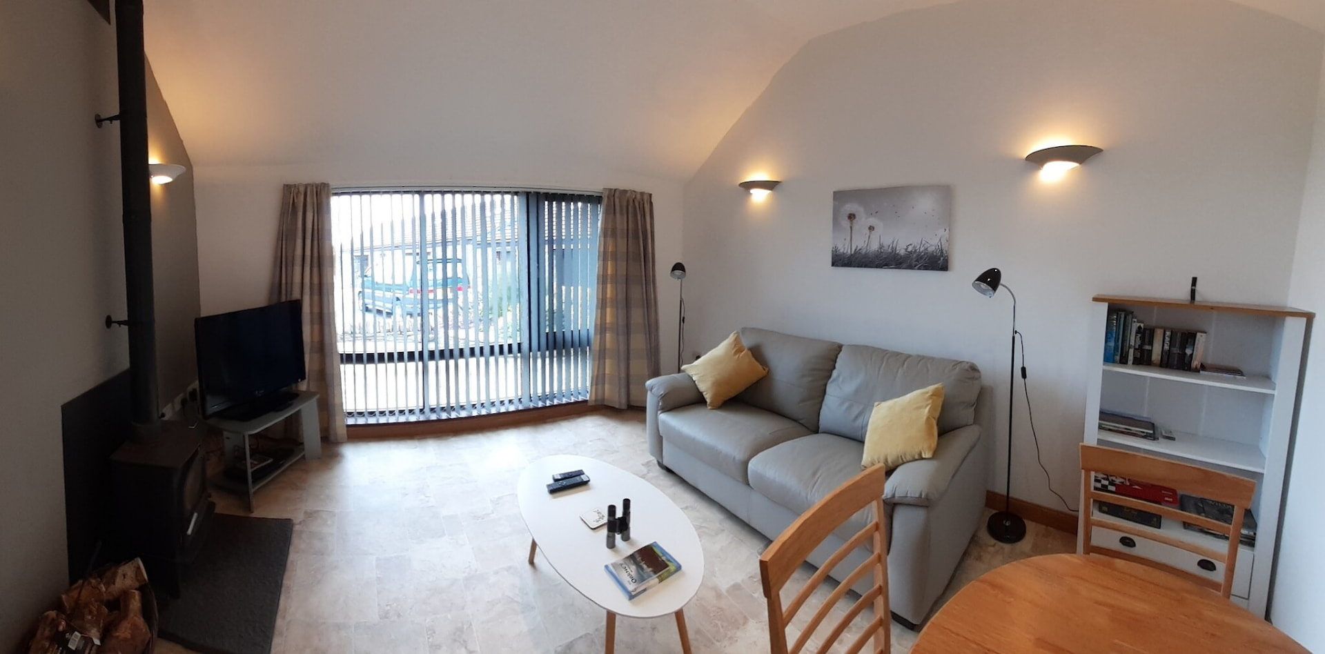 Living area with sofa, wood burning stove and patio doors
